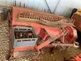 une machine rouge qui est à l'arrêt dans la poussière