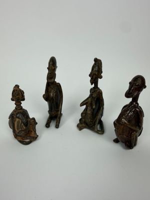quatre figurines en bronze représentant des personnes assises sur une surface blanche