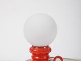 a red table lamp with a white ball on top of it