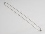 a silver necklace with a star on it sitting on top of a white surface