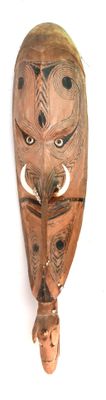 un masque en bois accroché à un mur, sur fond blanc