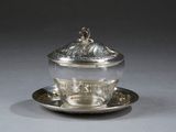 assiette en argent avec un couvercle en argent et une soucoupe en argent posée sur une soucoupe