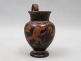 an old black and red vase sitting on top of a table