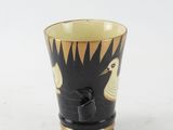 a black and gold cup with a bird design on it