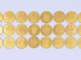 un gros plan sur une rangée de pièces d'or posées sur une surface blanche