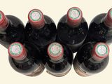 six bottles of wine are lined up in a row on a white surface
