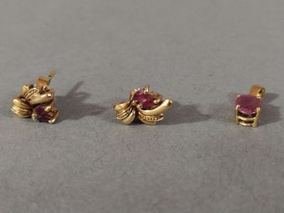 three pairs of gold and ruby earrings on a gray surface