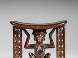 une petite sculpture en bois représentant un homme assis sur un tabouret