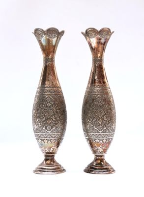 two silver vases sitting next to each other on a white surface