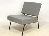 chaise grise aux pieds noirs, posée sur un sol blanc