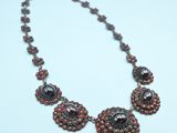 a close up of a necklace on a table with a blue background
