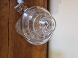 a glass vase on a wooden table next to a white wall