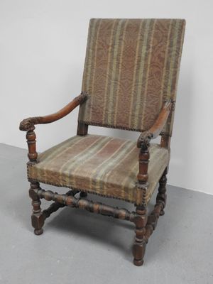 une vieille chaise dont l'assise rembourrée est usée et qui a des pieds en bois