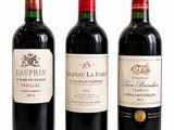 three bottles of red wine are lined up on a white surface