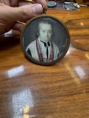 a person holding a miniature picture of a man on a table