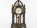 a clock with a statue on top of it on a table