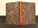 an old book sitting on top of a black table next to a white wall
