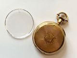a gold pocket watch sitting next to a glass of water