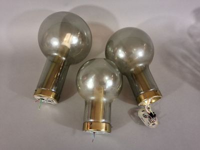 three silver and gold light bulbs on a white surface
