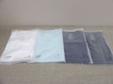 four t - shirts are lined up in a row on a bed