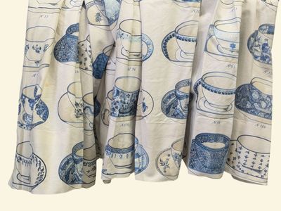 une photo d'un rideau orné de tasses à thé bleues et blanches