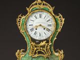 a green and gold clock sitting on a table