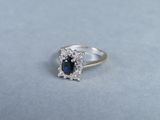 a close up of a blue sapphire and diamond ring on a gray surface