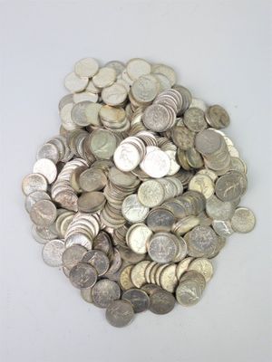 un tas d'argent et de pièces d'argent posés sur une surface blanche