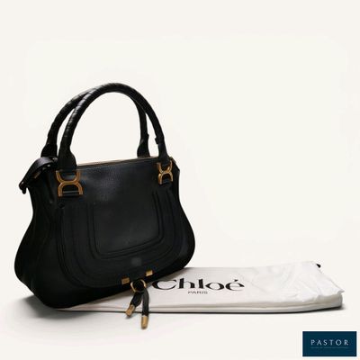 the small black purse is next to a white bag on a white surface