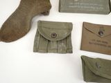 several military items are displayed on a white surface, including a pair of boots
