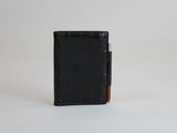 un portefeuille noir surmonté d'un porte-cartes, posé sur une surface blanche
