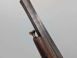 a close up of a gun with a wooden handle on a gray background