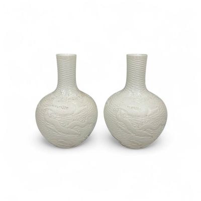 une paire de vases blancs posés l'un sur l'autre sur une surface blanche
