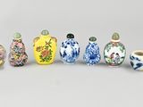 six small vases are lined up in a row on a gray surface