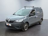 La camionnette grise est garée dans une pièce blanche au sol noir.