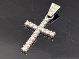pendentif en forme de croix en argent orné de pierres blanches sur un fond noir