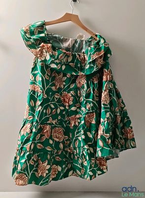 a green dress hanging on a hanger against a white wall