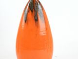an orange vase with black spots on it on a white surface
