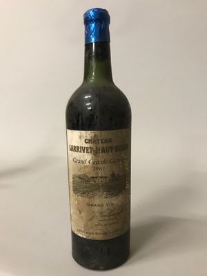 une vieille bouteille de vin posée sur une table blanche