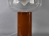 an orange table lamp with a clear glass shade on top of it