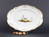 un gros plan sur une assiette sur laquelle sont disposés un oiseau et des noix
