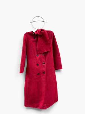 the red coat is hanging on a hanger on a white wall