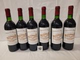 six bouteilles de vin sont alignées sur une table