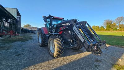 the tractor is parked in front of the barn on the dirt