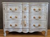 a white chest of drawers with gold handles on it