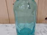 une bouteille en verre bleue munie d'un bec verseur en métal, posée sur une table