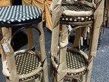 deux tabourets en carton et une table dont le plateau est à carreaux noirs et blancs