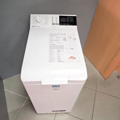 une machine à laver blanche posée à même le sol dans une salle de bains