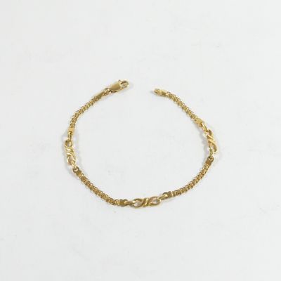 un bracelet en chaîne dorée orné d'un motif de nœud sur fond blanc