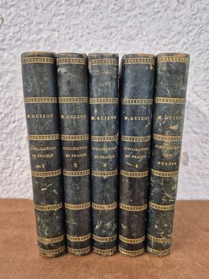 a set of five old books sitting on top of a wooden table